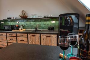 埃格尔Eger Castle Hill Premium Apartments的厨房配有黑色冰箱和2杯葡萄酒