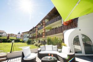 卡斯特尔罗托卡斯特勒塞尔森阿姆公寓式酒店的配有白色家具和绿色遮阳伞的庭院