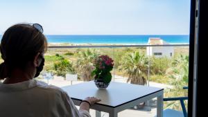 萨阿拉德洛斯阿图内斯Hotel Playa de la Plata的坐在桌子上看着大海的女人