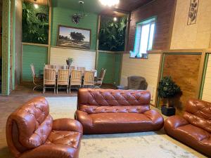 Hora格林别墅酒店的客厅配有棕色皮革家具和桌子