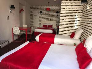 马孔协和酒店的一间卧室配有两张红色和白色床单