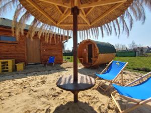 耶维克Ośrodek Wypoczynkowy IGOR nad Jeziorem Żywieckim的海滩上遮阳伞下的桌椅