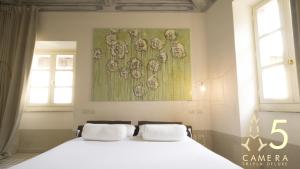 维泰博Guest House A Via dei Pellegrini的卧室配有一张白色床,墙上挂有绘画作品