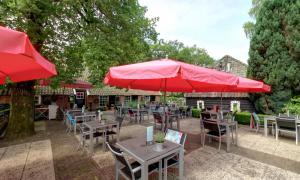 Diffelen格鲁普农场餐厅酒店的一个带桌椅和红伞的庭院