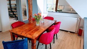 锡克Villa Appartements Syke的一间带木桌和红色椅子的用餐室