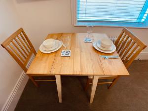 韦茅斯Self Contained Guest Suite 1 - Weymouth的一张木桌,配有两把椅子和盘子,酒杯
