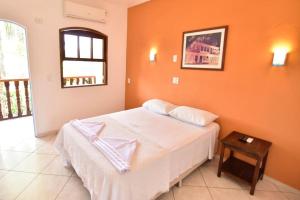 帕拉蒂Hotel Velejador的卧室配有白色的床和橙色的墙壁