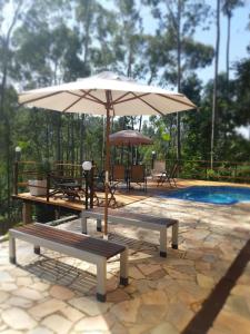 佩尼多Bendito Recanto的庭院设有2个长椅和1把遮阳伞,毗邻游泳池