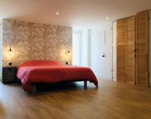 卡朗唐Le Salon de l'Isle的一间卧室设有红色的床,铺有木地板。