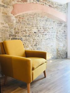 卡朗唐Le Salon de l'Isle的砖墙房间里一张黄色椅子