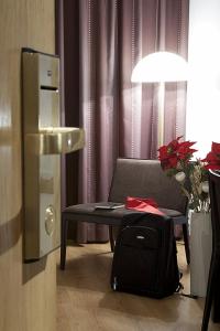 赫塔费卡洛斯三世旅馆的一间带椅子和一张带行李箱的桌子的房间