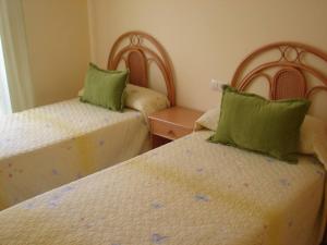桑亨霍Apartamento Lima的卧室内的两张带绿色枕头的床