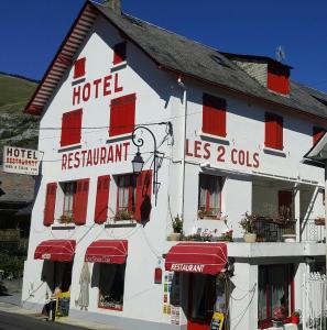 圣玛丽德康庞Hôtel les Deux Cols的一间大型白色酒店,在街上设有红色百叶窗