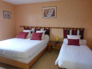 于讷河畔索镇Logis hôtel Les Confins du perche的配有白色和红色枕头的酒店客房内的两张床