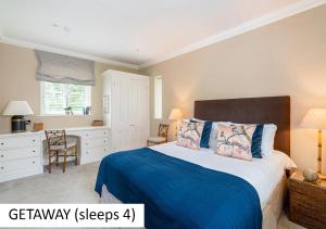 卡德纳姆Cadnam Lodge的一间卧室配有一张带蓝毯的床和一张书桌