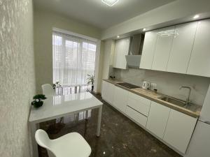 罗夫诺2 кімнатні ,Люкс апартаменти в ЖК Арена ,район автовокзалу的厨房配有白色橱柜和白色椅子