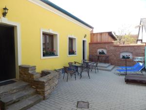 克塞洛Boros Vendégház I.的黄色的房屋设有带桌椅的庭院