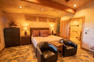 托里Cougar Ridge的一间卧室配有一张床和两张皮椅