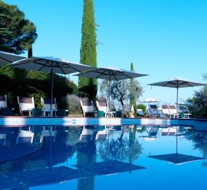 圣吉米纳诺Relais Santa Chiara Hotel - Tuscany Charme的一个带椅子和遮阳伞的游泳池