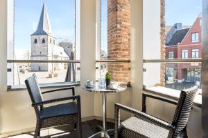 代讷坎普德史特酒店的阳台配有桌椅,享有教堂的景致