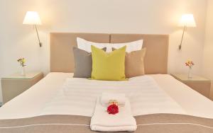 MöhlinBata Club Haus的白色的床,上面有白色的毯子和鲜花