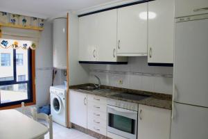 桑亨霍Apartamento Lima的厨房配有白色橱柜、水槽和洗碗机。