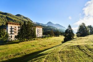 马洛亚Maloja Palace Residence Engadin-St Moritz CO2-Neutral的一座山丘上的建筑,背景是山丘