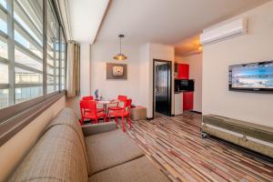 特拉维夫本叶湖达公寓式酒店的客厅配有沙发和带红色椅子的桌子