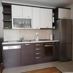 格拉达茨Musa apartment的厨房配有白色橱柜和不锈钢冰箱