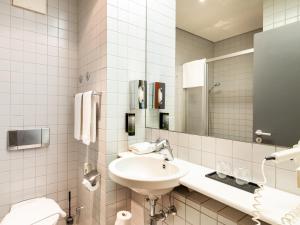 美因河畔法兰克福Plaza Hotel & Living Frankfurt的白色的浴室设有水槽和镜子