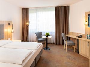 美因河畔法兰克福Plaza Hotel & Living Frankfurt的酒店客房带一张床、一张桌子和椅子