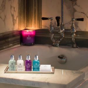 拉尼德洛伊斯Unicorn Hotel的浴室水槽配有4瓶肥皂和蜡烛
