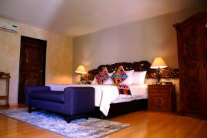 克雷塔罗米纳斯传统皇家酒店的一间卧室配有一张大床和一张蓝色椅子