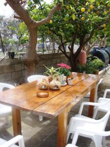 阿吉亚努美利阿蒂米斯公寓酒店的一张带白色椅子的木桌和橘子树