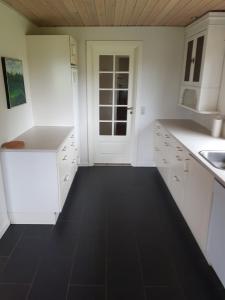 DybvadElmely的厨房配有白色橱柜和黑色地板