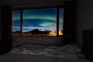 霍芬牛奶厂住宿加早餐旅馆的一间卧室设有窗户,享有北极光的景致。