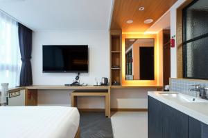 水原市S Stay Hotel的酒店客房设有床、电视和水槽。