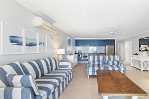 赫维湾Hamptons Meets Hervey Bay In Upmarket Resort - Ocean Views的一间带蓝白条纹沙发的客厅和一间厨房