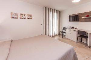 拉蒂萨纳Hotel Ristorante Cigno的白色卧室配有床和书桌