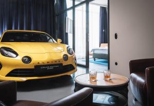 慕尼黑AMERON München Motorworld的停在客厅的黄色汽车,客厅里配有桌子