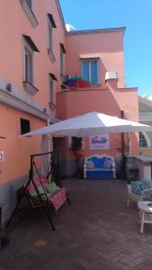 普罗奇达Il Borghetto Apartments & Rooms的粉红色建筑前的白色大伞