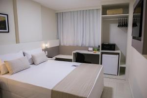UbáTrip Hotel Ubá的卧室配有一张白色大床和一张书桌