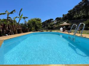 卡斯卡伊斯Quinta da Villa的一座大型蓝色游泳池,人们坐在雨伞下
