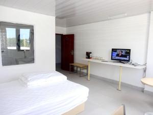 维拉港航空商务酒店 的白色的卧室配有一张床和一张书桌上的电脑