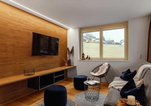 瓦尔德阿尔贝格Verwall Apartment Arlberg - mit Sauna, Balkon und Gästekarte Premium的客厅设有木墙,配有平面电视。