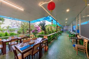 大叻Bonjour Da Lat Hotel的餐厅设有木桌和椅子,种有植物