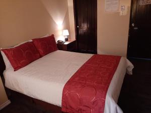 基多Hotel Bonaventure的一间卧室配有一张带红色枕头的大床