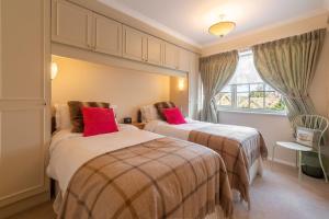 米德尔赫姆Fox Cottage的两张位于酒店客房的床铺,配有红色枕头
