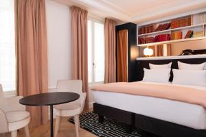 巴黎卢浮蒙大拿酒店的一间卧室配有一张大床和一张桌子及椅子