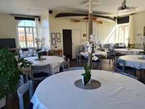 桑德港Missionshuset Bed & Breakfast的配有桌椅和白色桌子及鲜花的房间